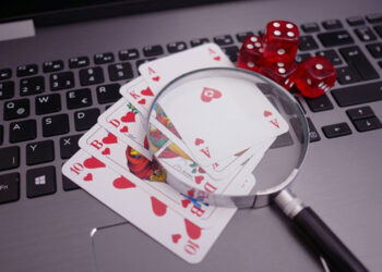 lupa y cartas de poker sobre pc