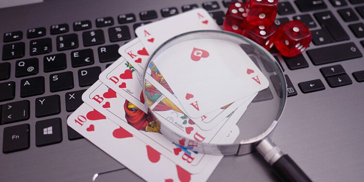 lupa y cartas de poker sobre pc